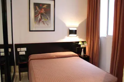 a bedroom with a bed and a lamp next to a window at Hotel Monegal in Barcelona
