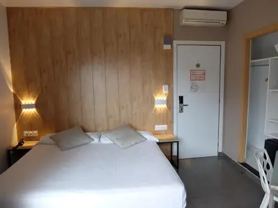 a bedroom with a large white bed and two lights at Hotel Medicis in Barcelona