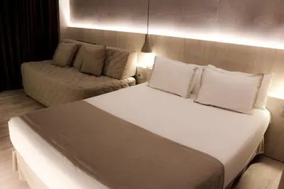 a bedroom with a white bed and a couch at Hotel Bernat II 4*Sup in Calella