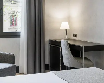 a hotel room with a desk and a chair at Ilunion Bel-Art in Barcelona