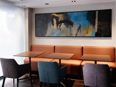 a waiting room with two tables and chairs and a painting at HG City Suites Barcelona in Barcelona