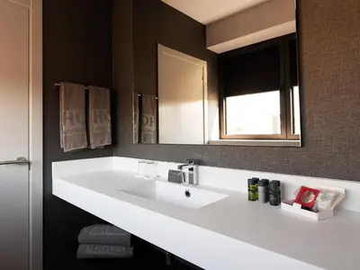 a bathroom with a white sink and a mirror at HG City Suites Barcelona in Barcelona