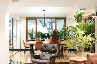 a woman sitting at a table in a room with plants at Arenas Atiram Hotel in Barcelona