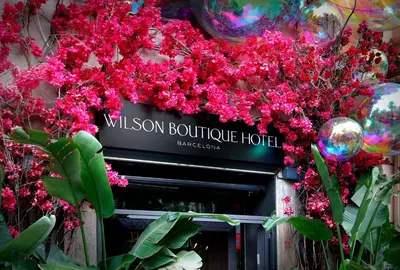 a sign for willson boutique hotel with pink flowers at Wilson Boutique Hotel in Barcelona
