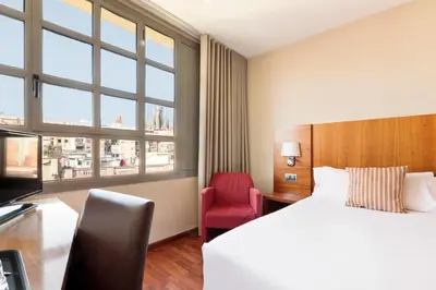 a hotel room with a bed and a red chair at Hotel Best Aranea in Barcelona
