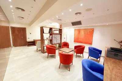 a waiting room with red chairs and a table at Garbi Millenni in Barcelona