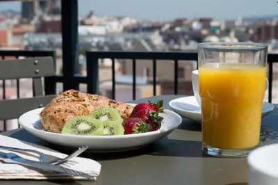 a plate of food with fruit and a glass of orange juice at Habitat Apartments Tessa in Barcelona