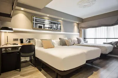 a hotel room with two beds and a desk and a desk at Acta Splendid in Barcelona