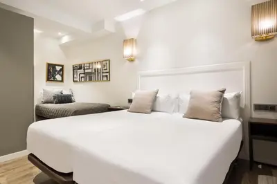 a white bedroom with a large white bed and a couch at Acta Splendid in Barcelona