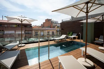a fountain in a pool with a table and an umbrella at Zenit Borrell in Barcelona