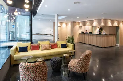 a lobby with couches and tables and paintings on the wall at Catalonia Diagonal Centro in Barcelona