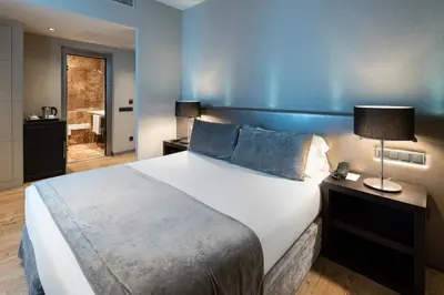 a bedroom with a large bed with a blue wall at Catalonia Portal de l'Angel in Barcelona