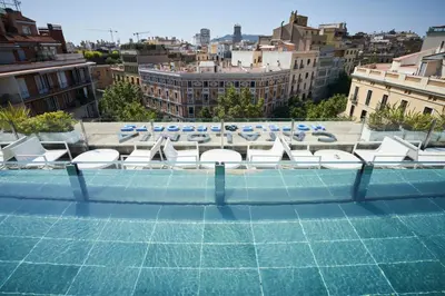 a row of white lounge chairs on a roof at Catalonia Eixample 1864 in Barcelona