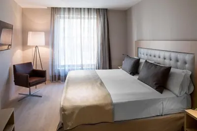 a bedroom with a large bed and a chair at Catalonia Sagrada Familia in Barcelona