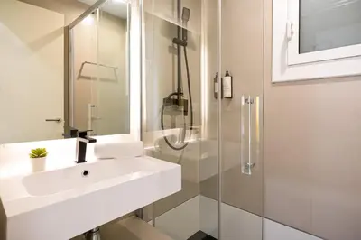 a white bathroom with a sink and a shower at Sitges Group Ocean in Sitges