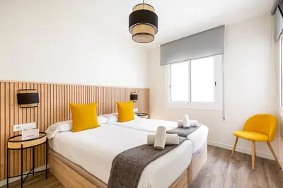 a bedroom with two beds and a yellow chair at Sitges Group Ocean in Sitges