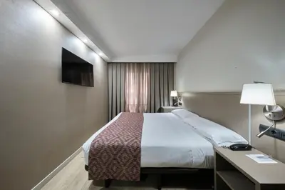 a hotel room with a large bed and a desk at Catalonia Park Güell in Barcelona