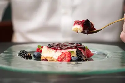 a person holding a piece of cake with berries on a fork at Catalonia Park Güell in Barcelona