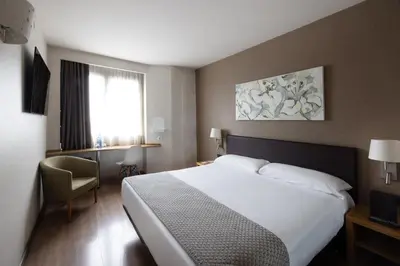 a hotel room with a bed and a chair and a television at Catalonia Albeniz in Barcelona