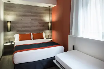 a small bedroom with two beds and a window at Catalonia Mikado in Barcelona