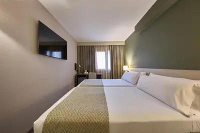 a hotel room with a large bed and a chair at Catalonia Park Putxet in Barcelona