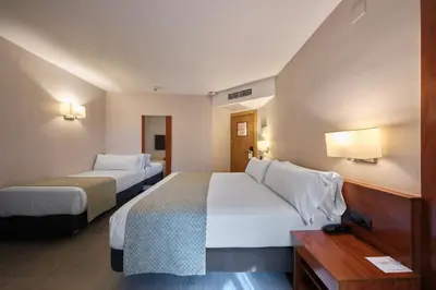 a hotel room with two beds and a desk at Catalonia Park Putxet in Barcelona