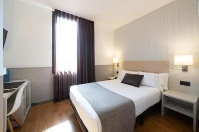 a hotel room with a large white bed and a window at Catalonia Gran Hotel Verdi in Sabadell