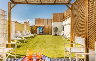 a patio with chairs and a lawn with drinks on it at Hotel Nouvel in Barcelona