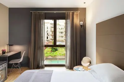 a bedroom with a bed and a desk and a window at Alexandra Barcelona Hotel, Curio Collection by Hilton in Barcelona