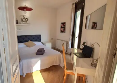 a bedroom with a bed and a desk with a laptop at Lovely Appart & Sky View SAGRADA FAMILIA in Barcelona