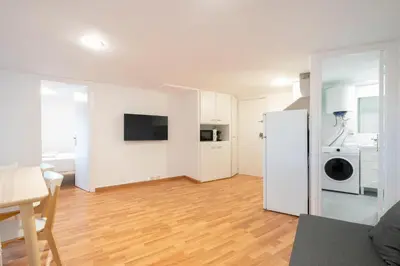 a living room with white walls and a wooden floor at Homenfun Barcelona Park Güell in Barcelona