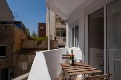 a balcony with a wooden table and a bottle of wine at Apartment close to the beach in Sant Adria de Besos