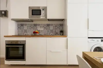 a kitchen with white cabinets and a microwave at Apartment close to the beach in Sant Adria de Besos