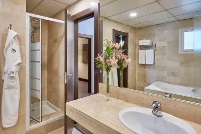 a bathroom with a sink and a vase of flowers at NH Barcelona Eixample in Barcelona
