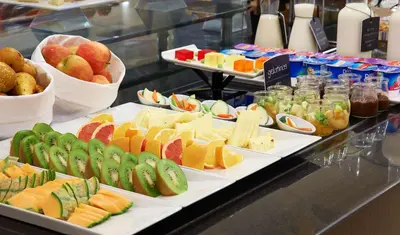 a buffet filled with different types of cheese and fruit at NH Barcelona Eixample in Barcelona