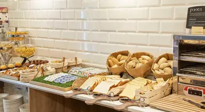 a bakery with bread and other foods on a shelf at NH Barcelona Les Corts in Barcelona