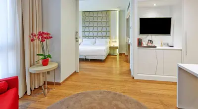 a hotel room with a bed and a red couch at NH Collection Barcelona Podium in Barcelona