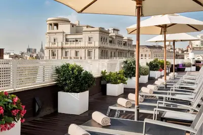 a row of white chairs and umbrellas on a balcony at NH Collection Barcelona Podium in Barcelona