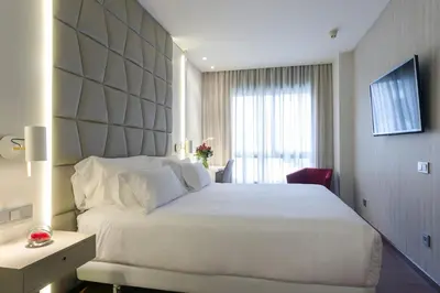 a bedroom with a large white bed and a window at NH Collection Barcelona Podium in Barcelona