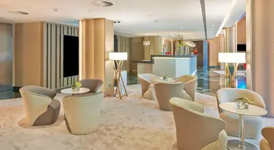 a lobby with tables and chairs in a building at NH Collection Barcelona Podium in Barcelona