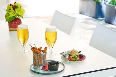 two glasses of beer and a plate of food on a table at NH Collection Barcelona Podium in Barcelona