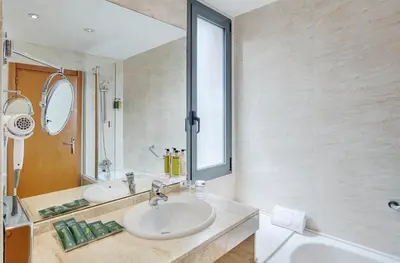 a bathroom with two sinks and a mirror and a tub at Sercotel Cornellà Barcelona in Cornellà de Llobregat