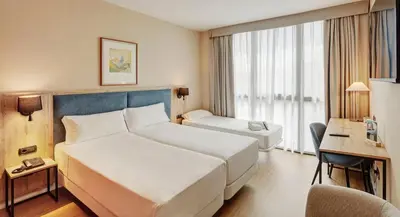 a hotel room with a large bed and a desk at Sercotel Cornellà Barcelona in Cornellà de Llobregat
