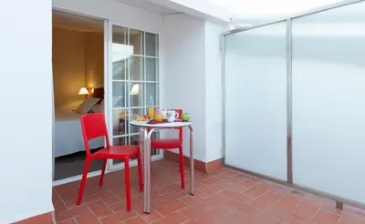 a room with a table and two red chairs at URH Ciutat de Mataró in Mataró