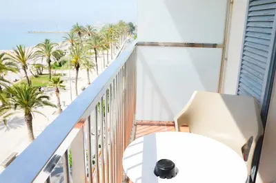 a balcony with a view of the beach and palm trees at Hotel Subur in Sitges