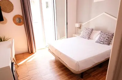 a bedroom with a bed with white sheets and pillows at Hotel Subur in Sitges