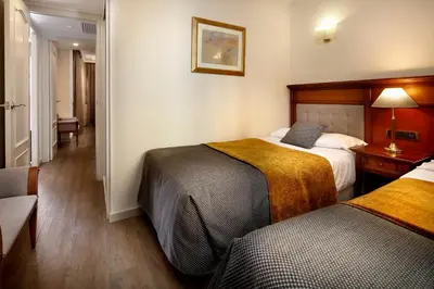a hotel room with two beds and a chair at Apartaments-Hotel Hispanos 7 Suiza in Barcelona