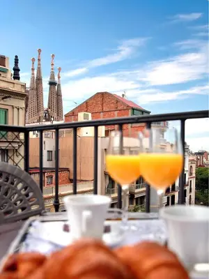 a table with two glasses of orange juice on a balcony at Apartaments-Hotel Hispanos 7 Suiza in Barcelona
