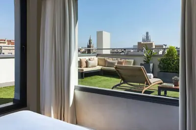 a room with a balcony with a chair and a couch at Renaissance Barcelona Hotel in Barcelona