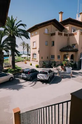 two cars parked in a parking lot in front of a building at Hotel Subur Maritim in Sitges